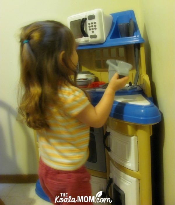 Three-year-old playing at her toy kitchen (she's left the terrible twos behind!)