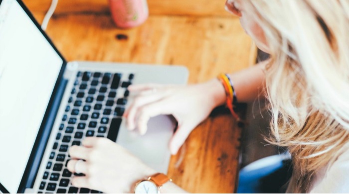 Woman typing on a laptop with a multi-tasking writing style.