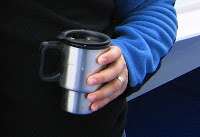 My husband holding his stainless steel coffe mug