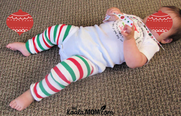 Baby's girl lays on the floor in her first Christmas onesie.