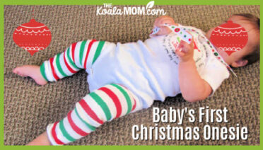 Baby's First Christmas Onesie and Leggings. Baby lays on floor wearing her white Christmas onesie and striped leggings.