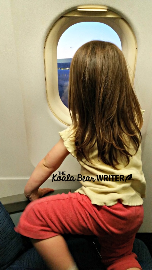 Toddler looking out the window of an airplane.