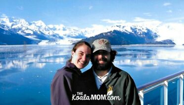 Couple posing in front of a glacier on their Alaska cruise honeymoon.