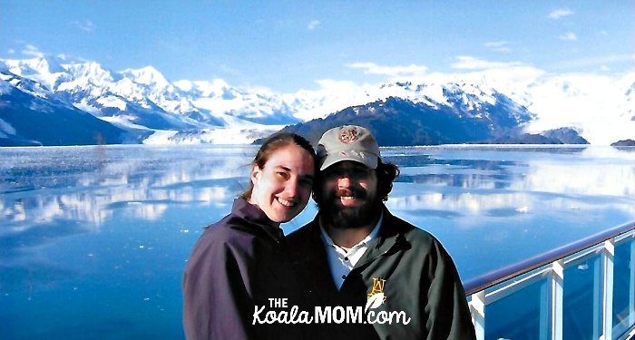 Couple posing in front of a glacier on their Alaska cruise honeymoon.