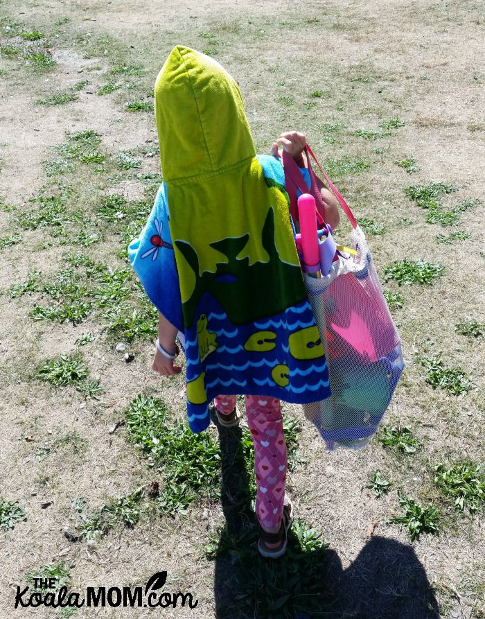 Sunshine leaving the beach, with her beach towel and toys