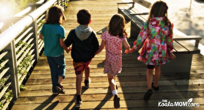 Four friends skipping along the sidewalk