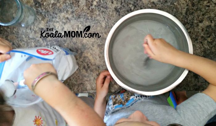 Sunshine and Lily mixing Epsom salt and water for a science experiment