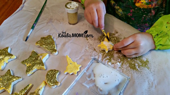 Jade adding glue and glitter to her salt dough magnets and ornaments. 