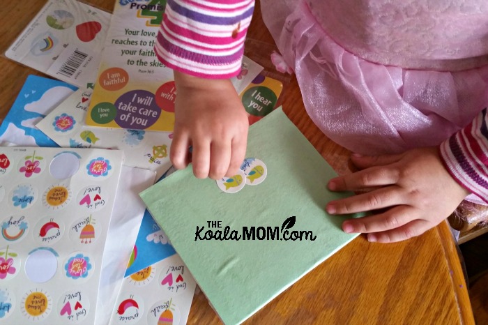 Toddler putting stickers on her notebook cover