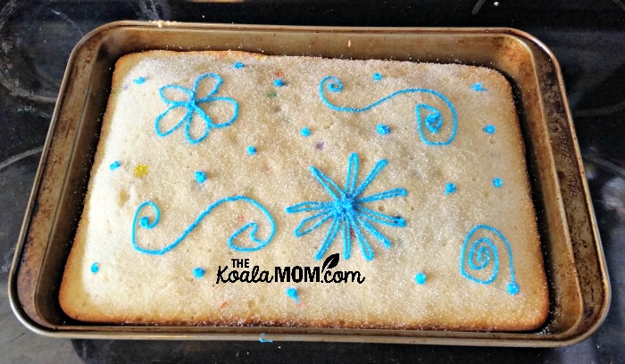 A square birthday cake with blue flowers on it