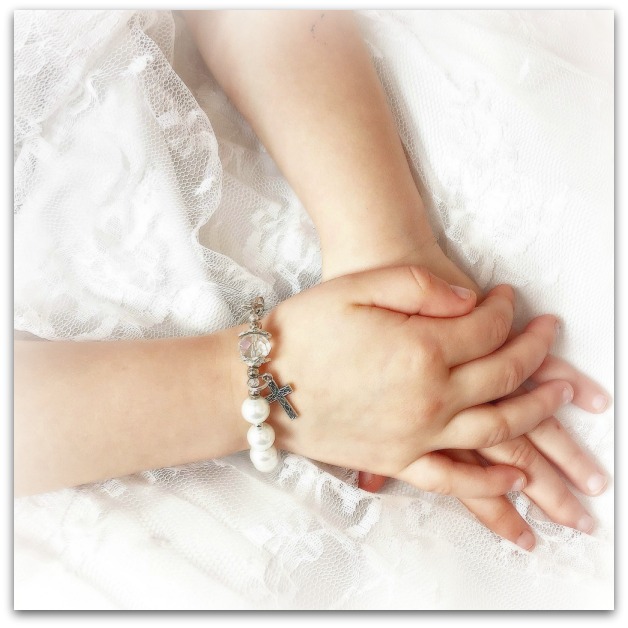 Girls' hands clasped with a rosary bracelet on her wrist