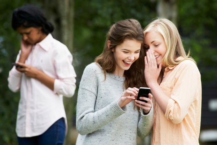 Teens texting together while leaving another teen out