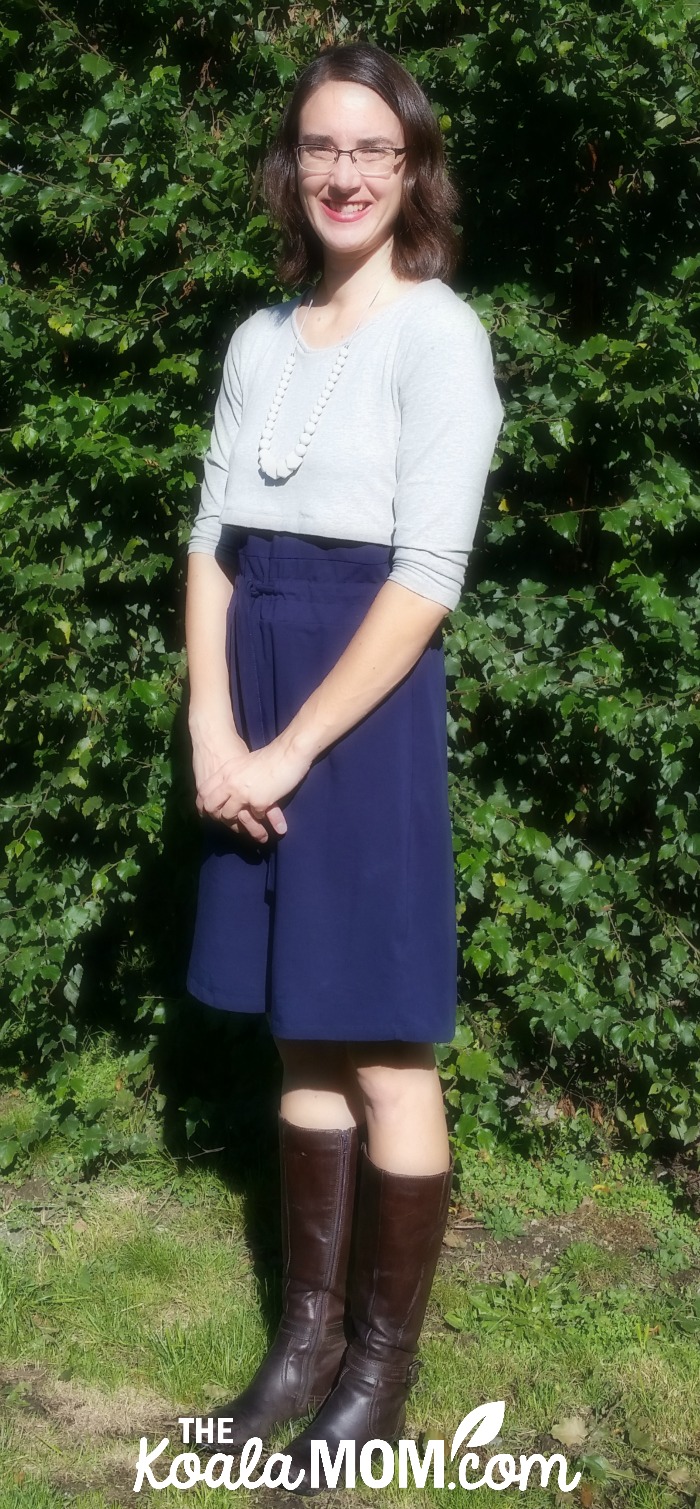 Mom wearing a blue-and-grey nursing dress from Momzelle with necklace from LouLou Lollipop and brown boots