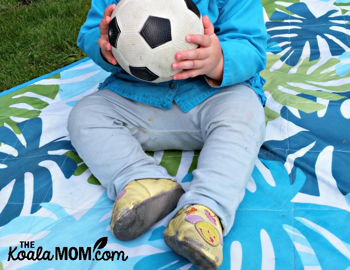 Baby holding a soccer ball while wearing kooshoo pants
