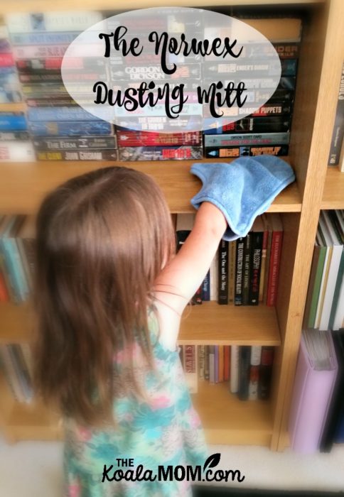 Toddler dusting bookshelves with the Norwex dusting mitt