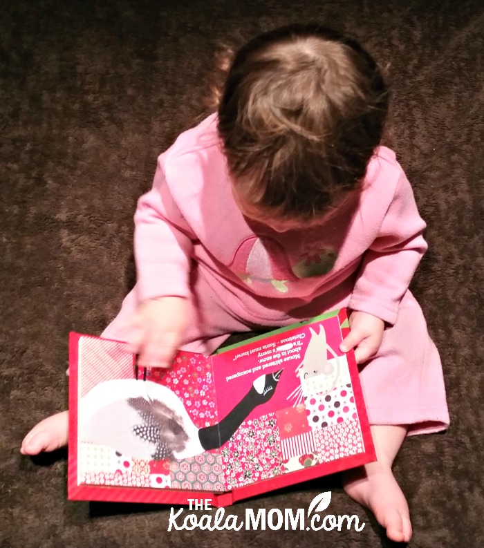 Baby girl reading a Christmas board book