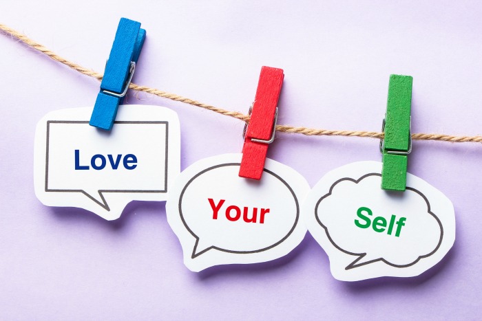 Love your self paper bubbles with clip hanging on the line against purple background.