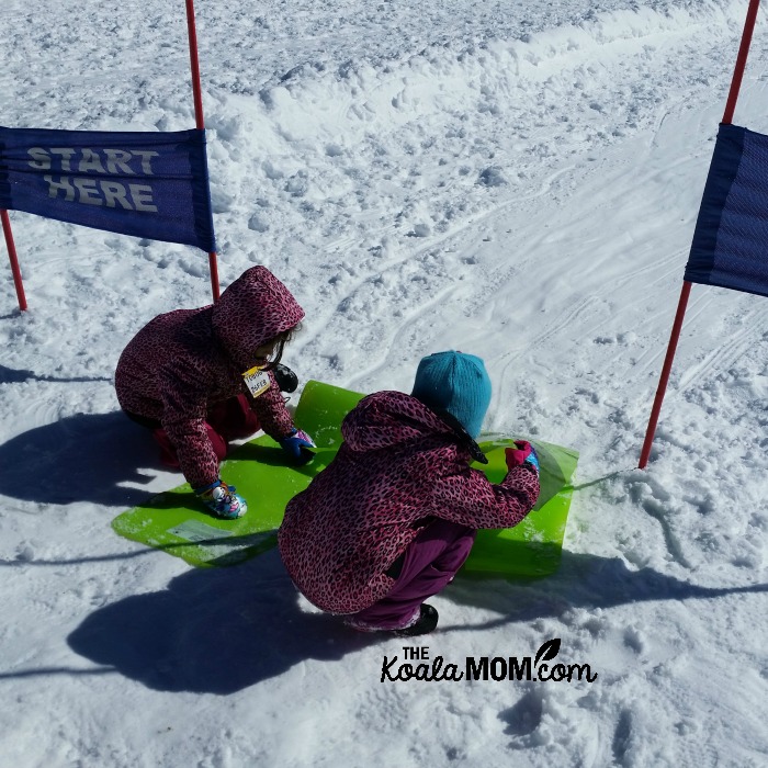 Two girls getting ready to ride their crazy carpets down the hill