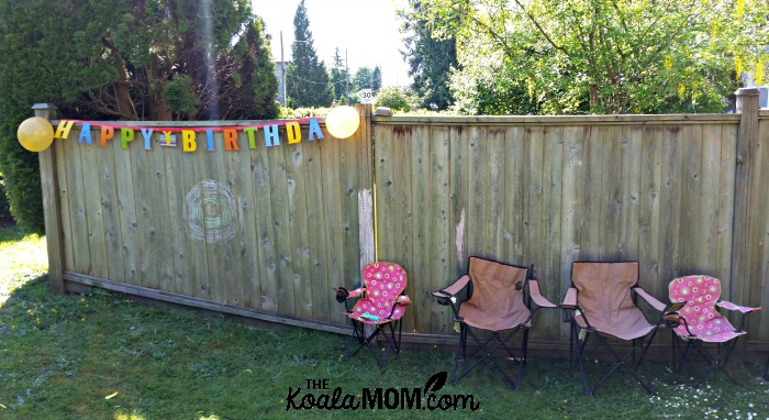 Our outdoor birthday party: happy birthday sign on the fence and lawn chairs to relax in
