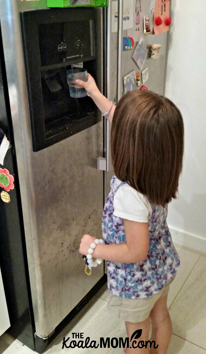 4-year-old Jade getting water for herself at the fridge.