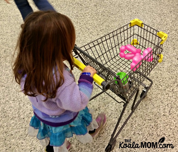 Toddler pushing a child-sized buggy at the grocery store