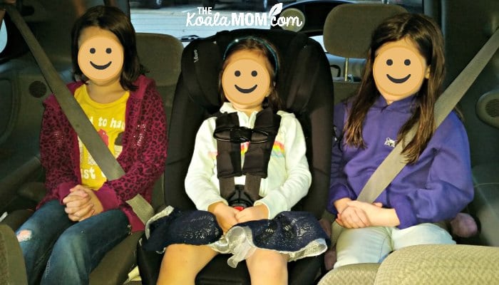 Three girls sitting in their car seats and booster seats in a Dodge Caravan