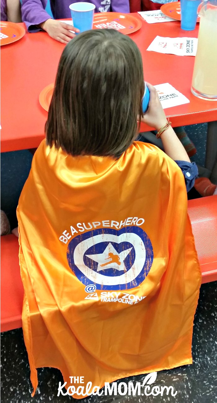 Jade wearing her "Be a Superhero" orange SkyZone cape at her birthday party.