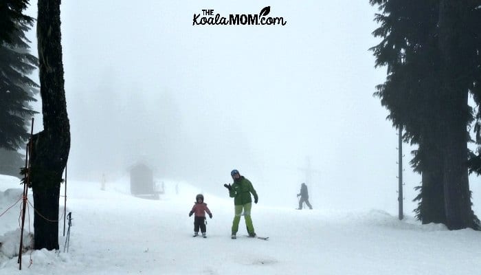 Four-year-old with her ski instructor, returning from a downhill skiing lesson.