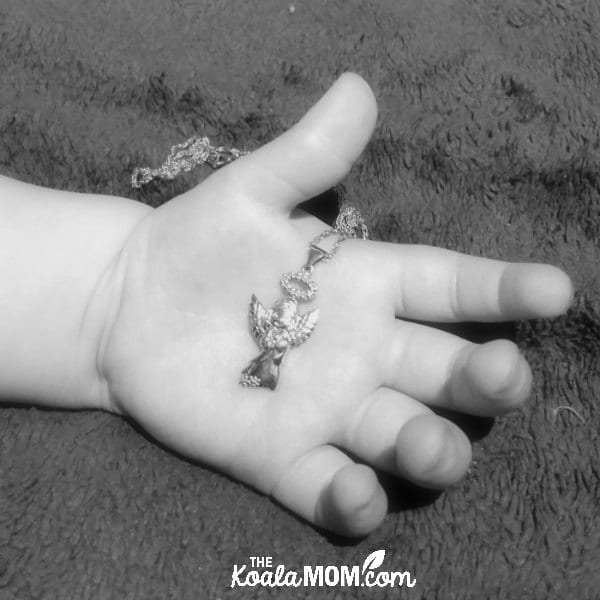 Two-year-old holding a silver Precious Moments necklace
