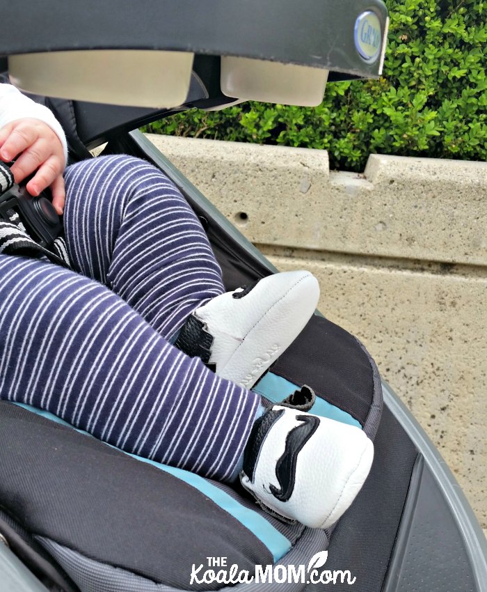 Baby in cute baby moccasins sitting in a stroller