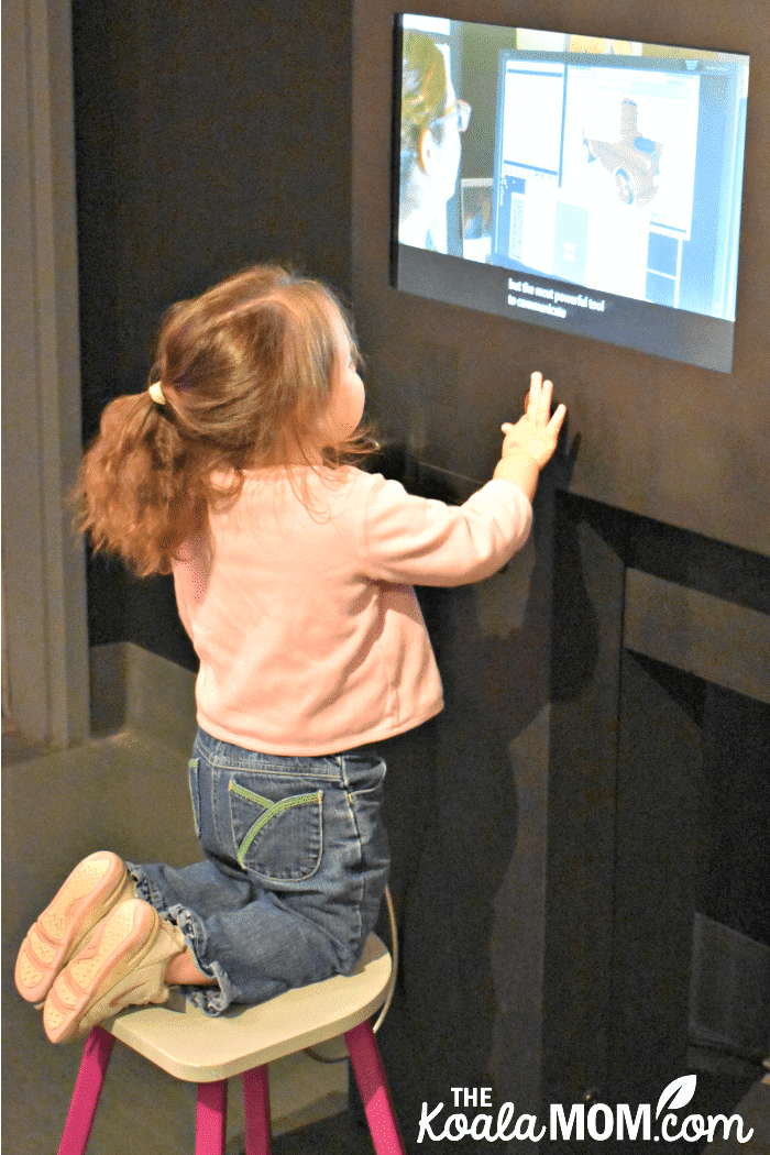 A toddler watches a Pixar interview at the Science Behind Pixar Exhibit.