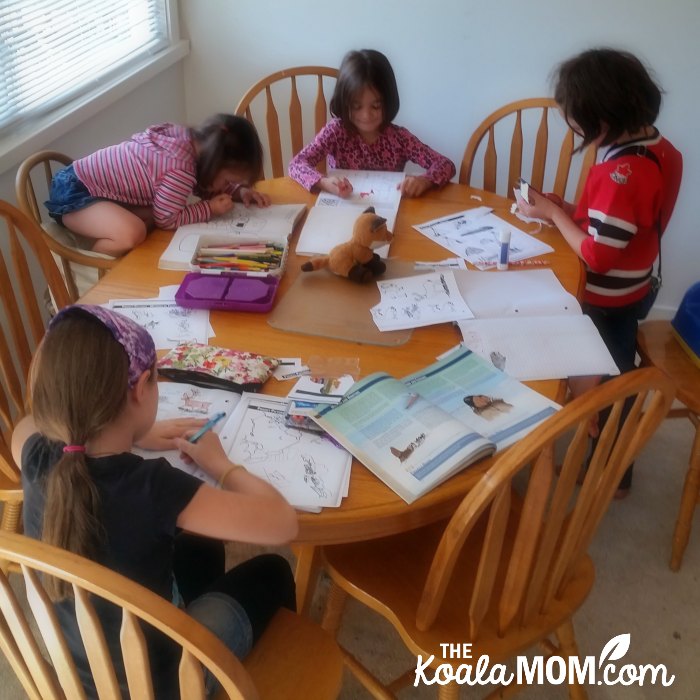 How to homeschool in BC like these four sisters doing their lessons around a dining room table.