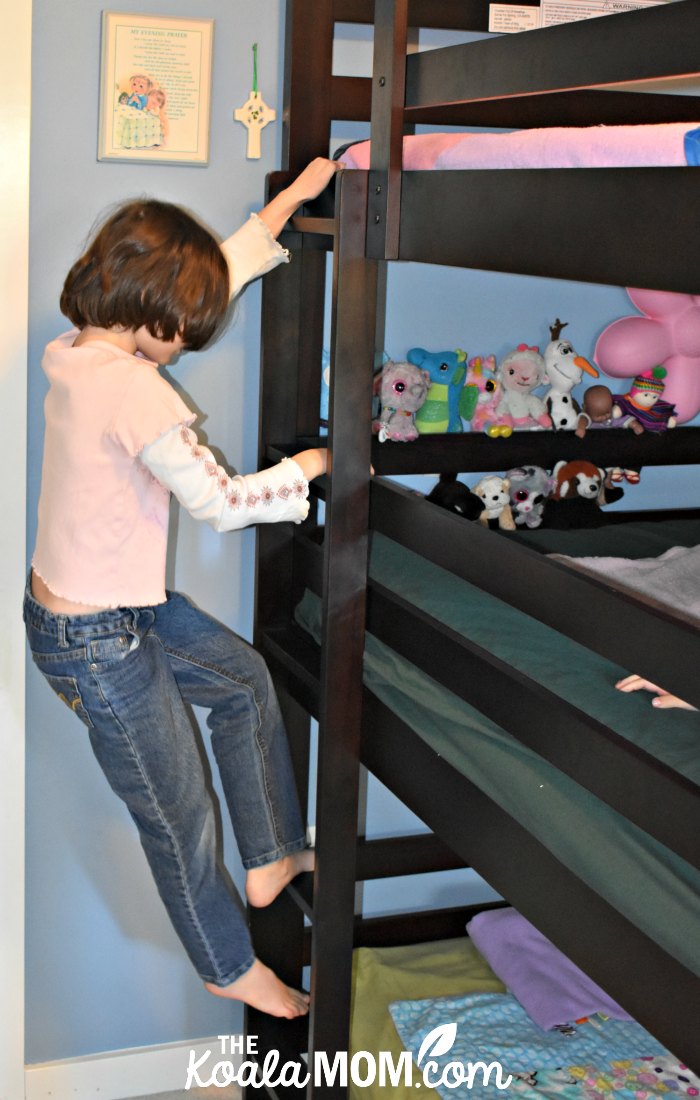 Girl climbing the ladder on her triple bunk bed.