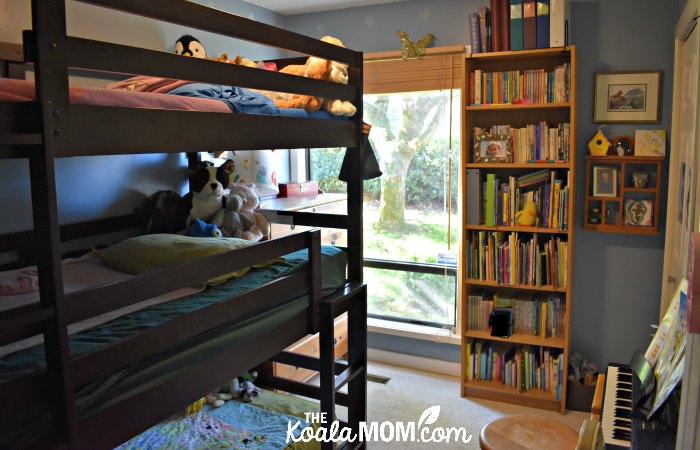 A girls blue bedroom with a triple bunk bed.