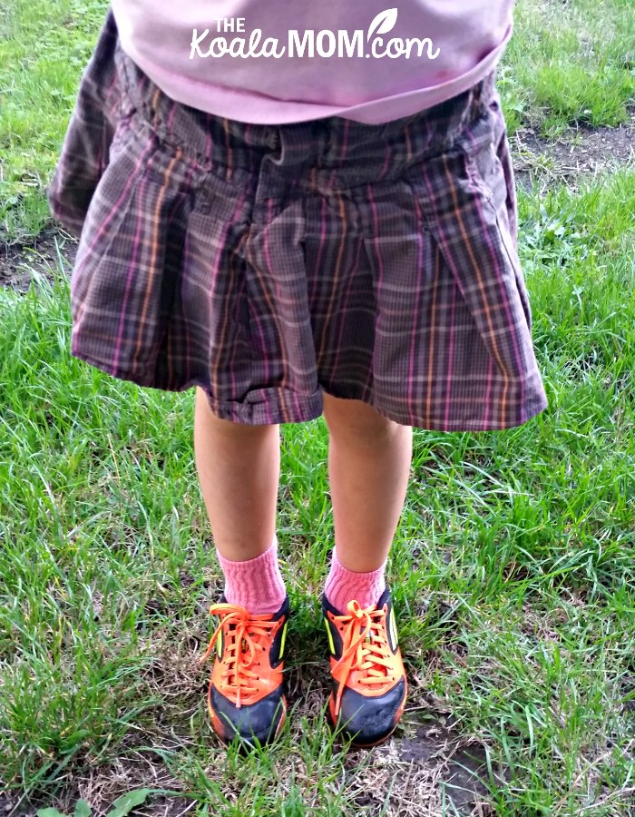 5-year-old wearing her orange rugby cleats and a plaid skirt - encourage your kids to play sports even if they give up easily!