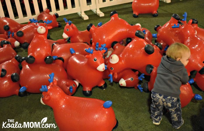 Baby in a pile of bouncy red reindeer.