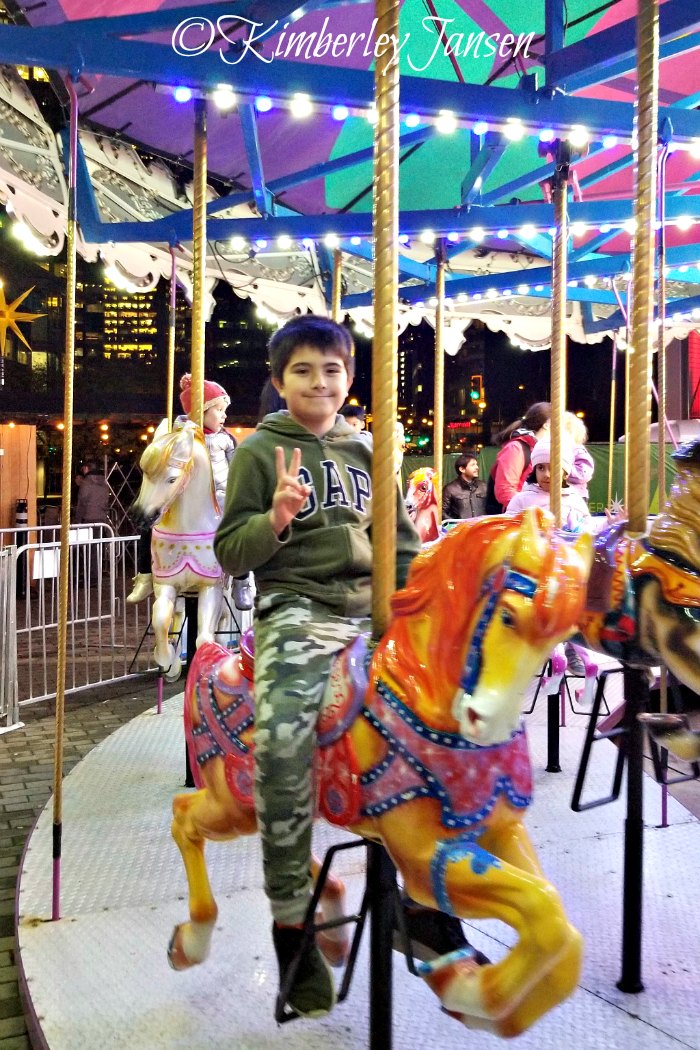 Boy riding the carousel at the Vancouver Christmas Market on a mother-son date night.