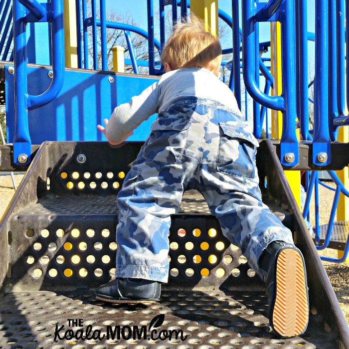 Baby climbing stairs on a playground.