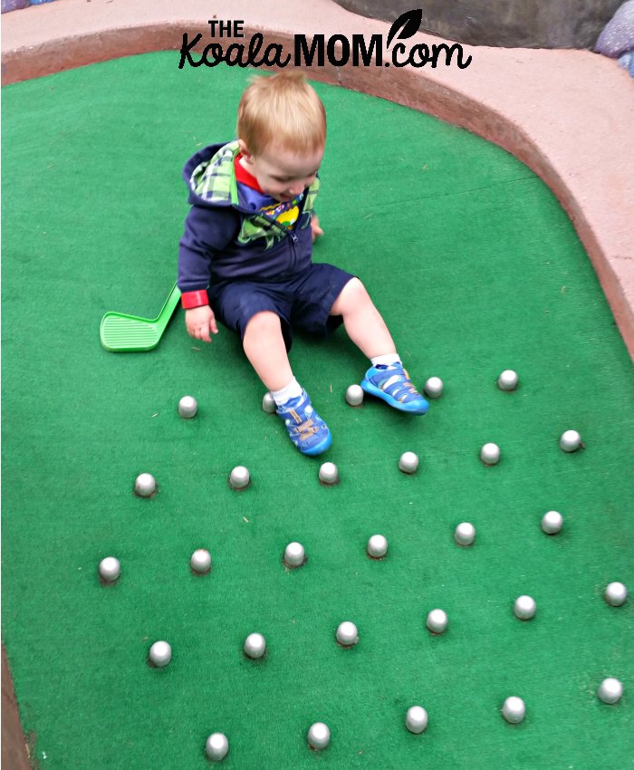 Toddler sliding down the mini golf course.