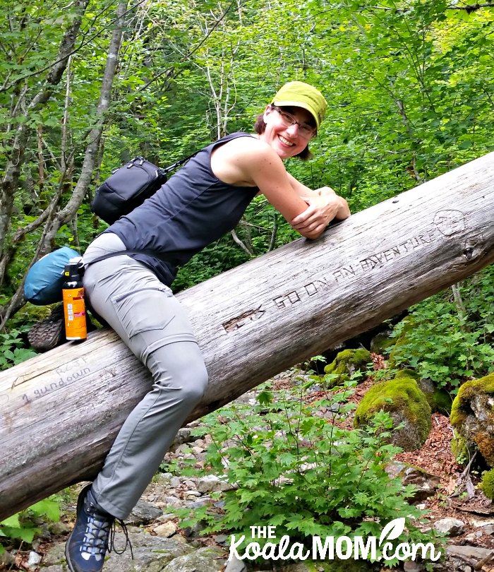 Bonnie Way sitting on a tree with "go on an adventure" carved in its trunk.