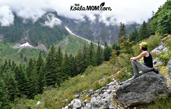 Bonnie Way sitting on a boulder, admiring the scenery in Golden Ears Park