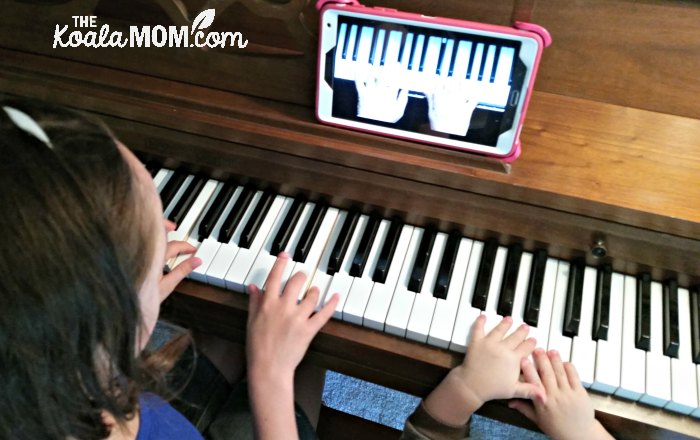 Girl learning piano online using a tablet.