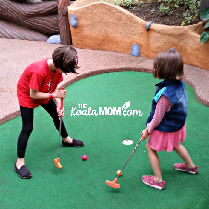 Two girls playing mini golf at Giggle Ridge.