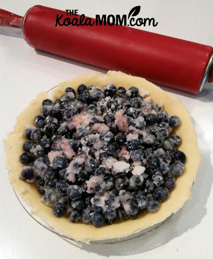 Making blue berry pie - open pie with a rolling pin sitting nearby.