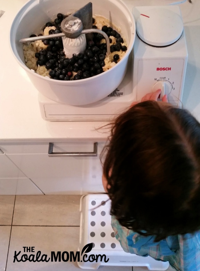 Toddler helping make muffins in a Bosch mixing machine.