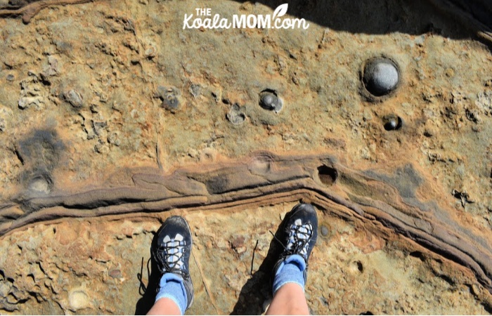 Hiker standing on brown sandstone rocks in blue boots.