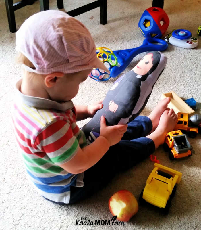 2-year-old boy holding a St. Elizabeth Ann Seton doll among his diggers and dumptrucks