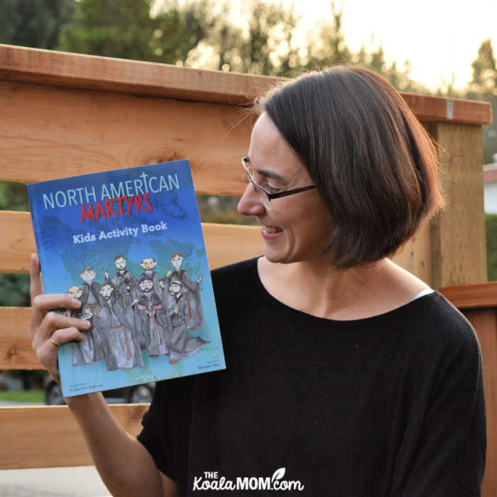 Bonnie Way holding her book, North American Martyrs Kids Activity Book