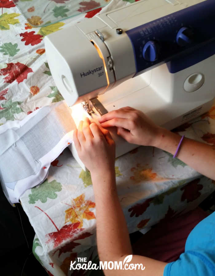 Sunshine sewing a doll for her siblings using a pattern from Faith and Fabric.