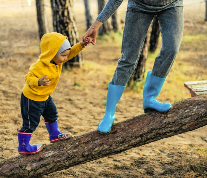Mom helping toddler climb log. Photo by VisionPic .net from Pexels